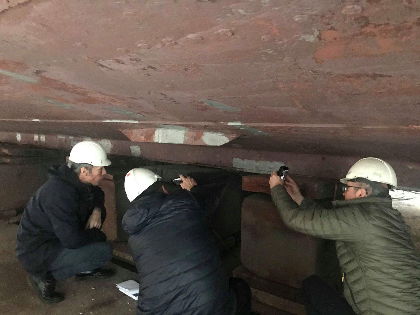 men under a ship in dry dock